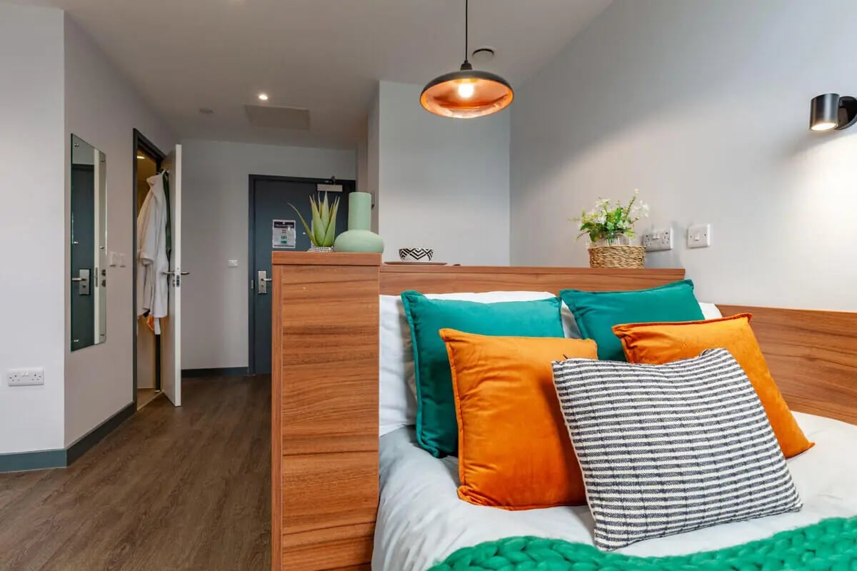 Bed with colorful pillows and hallway view bedroom at Straits Garden in Egham Student Accommodation