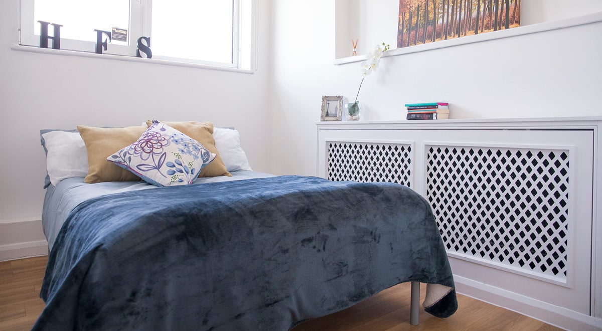 Bed with blue blanket pillows radiator cover Bedroom at Portobello Garrow House in London Student Accommodation