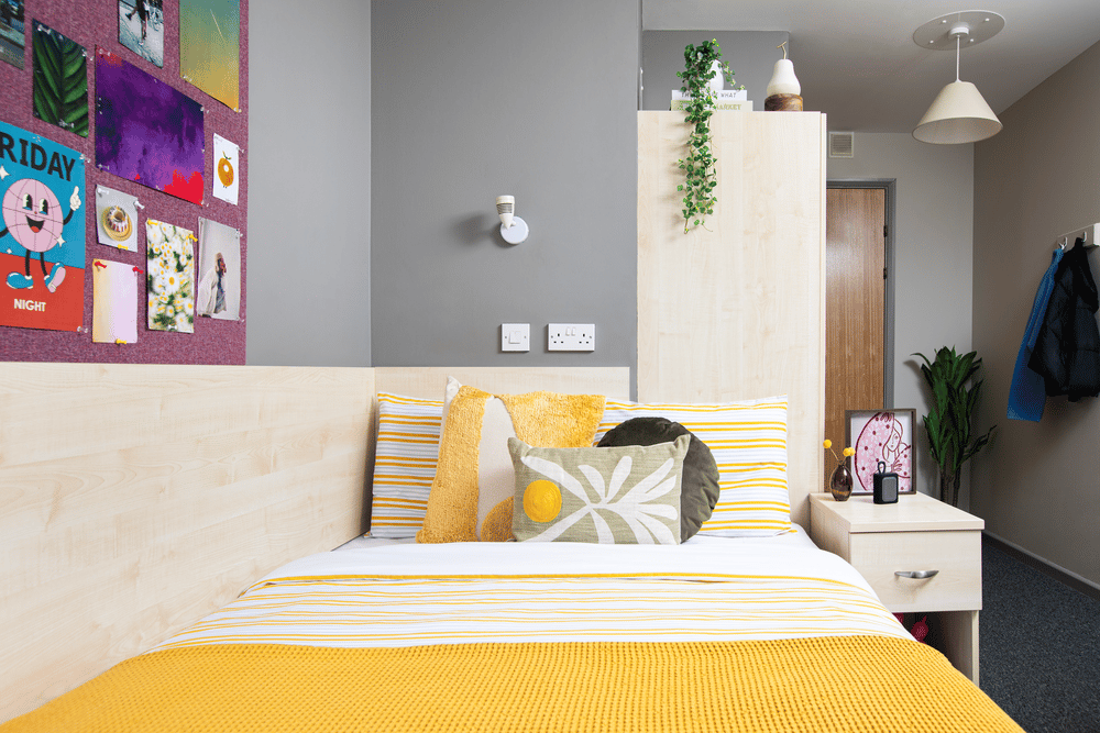 Bed with yellow bedding and decorative pillows bedroom at Newarke Point in Leicester Student Accommodation