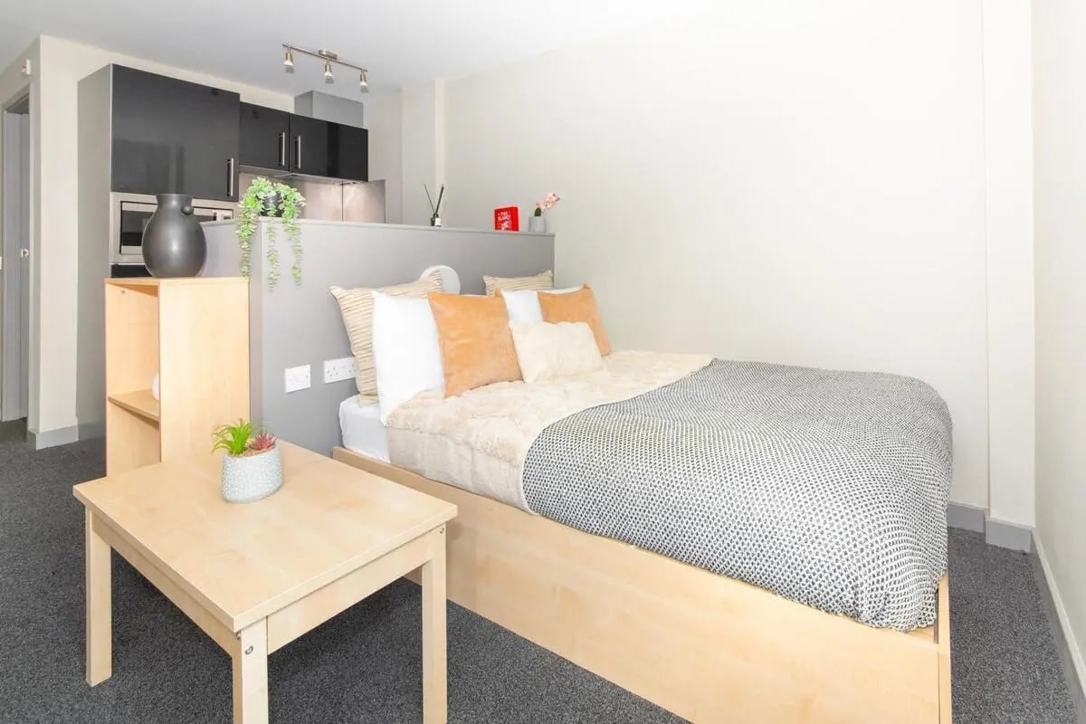 Bed with pillows and blanket small table bedroom studio at Studio 58 in Bristol Student Accommodation