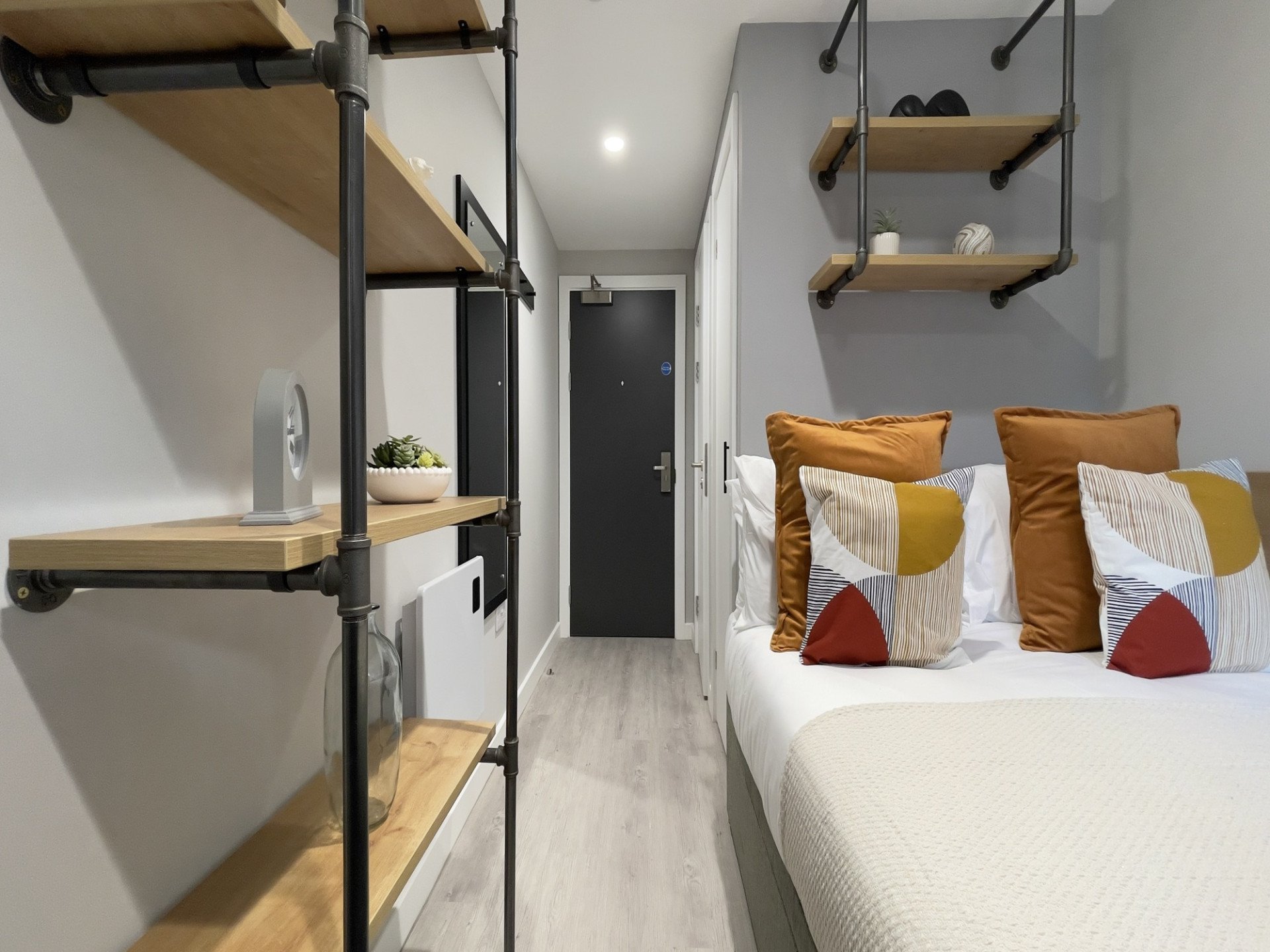 Bed with cushions shelves and door Bedroom at The Coal Yard in York Student Accommodation