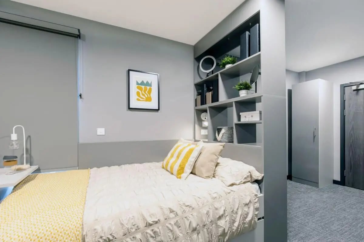 Bed with yellow blanket and shelves bedroom at Ash Grove Court - Guildford in Guildford Student Accommodation