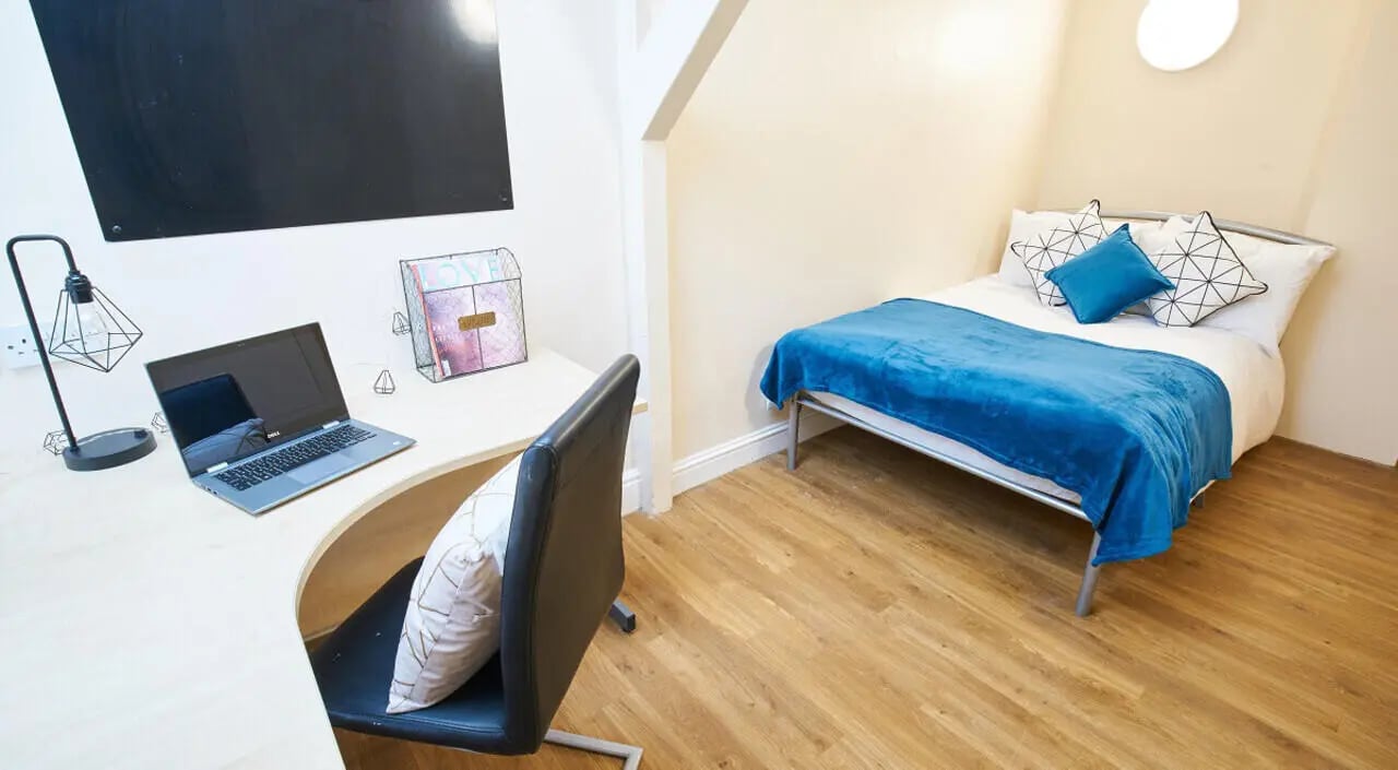 Desk with laptop bed with blue blanket bedroom at Daisybank Villas in Manchester Student Accommodation