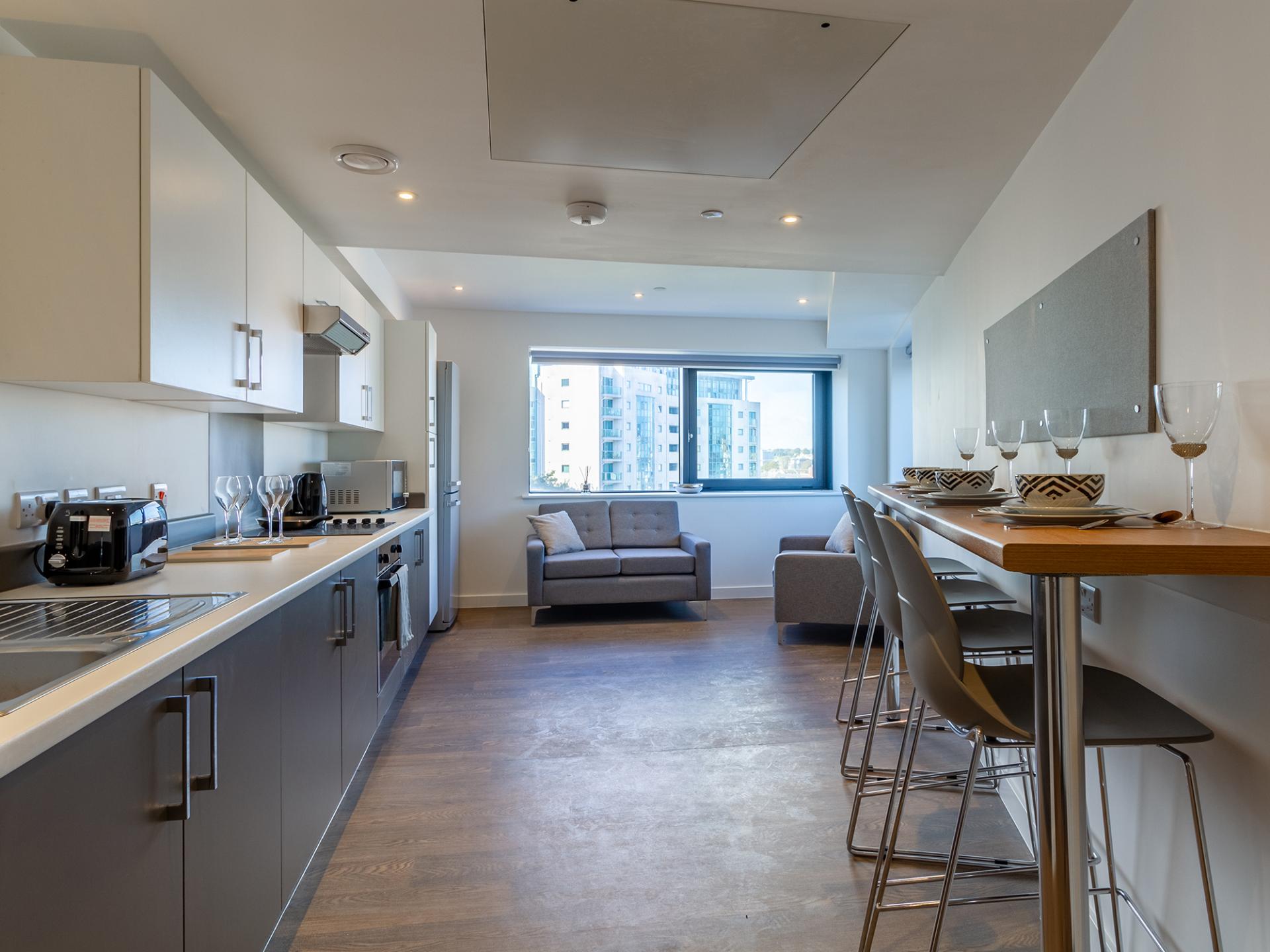 Kitchen with bar seating and living area at Saltwater Place in Plymouth Student Accommodation