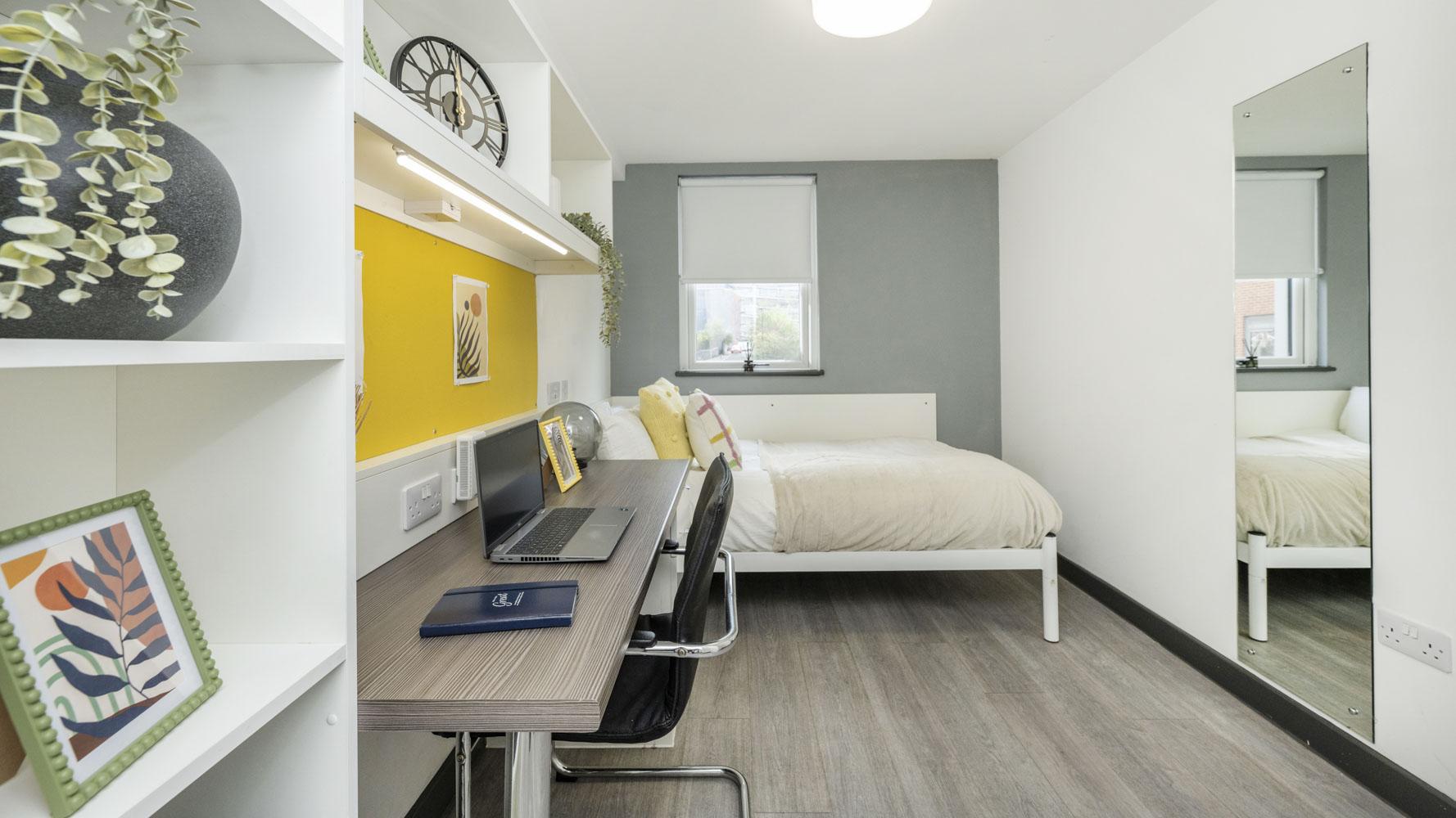 Desk plant framed art bed with pillows and mirror bedroom at Albert Place in Newcastle Upon Tyne Student Accommodation