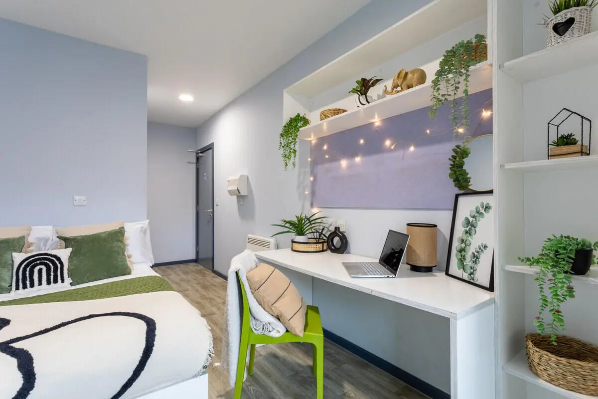 Bed with green pillows desk laptop plants bedroom at dwell Archer House in Nottingham Student Accommodation